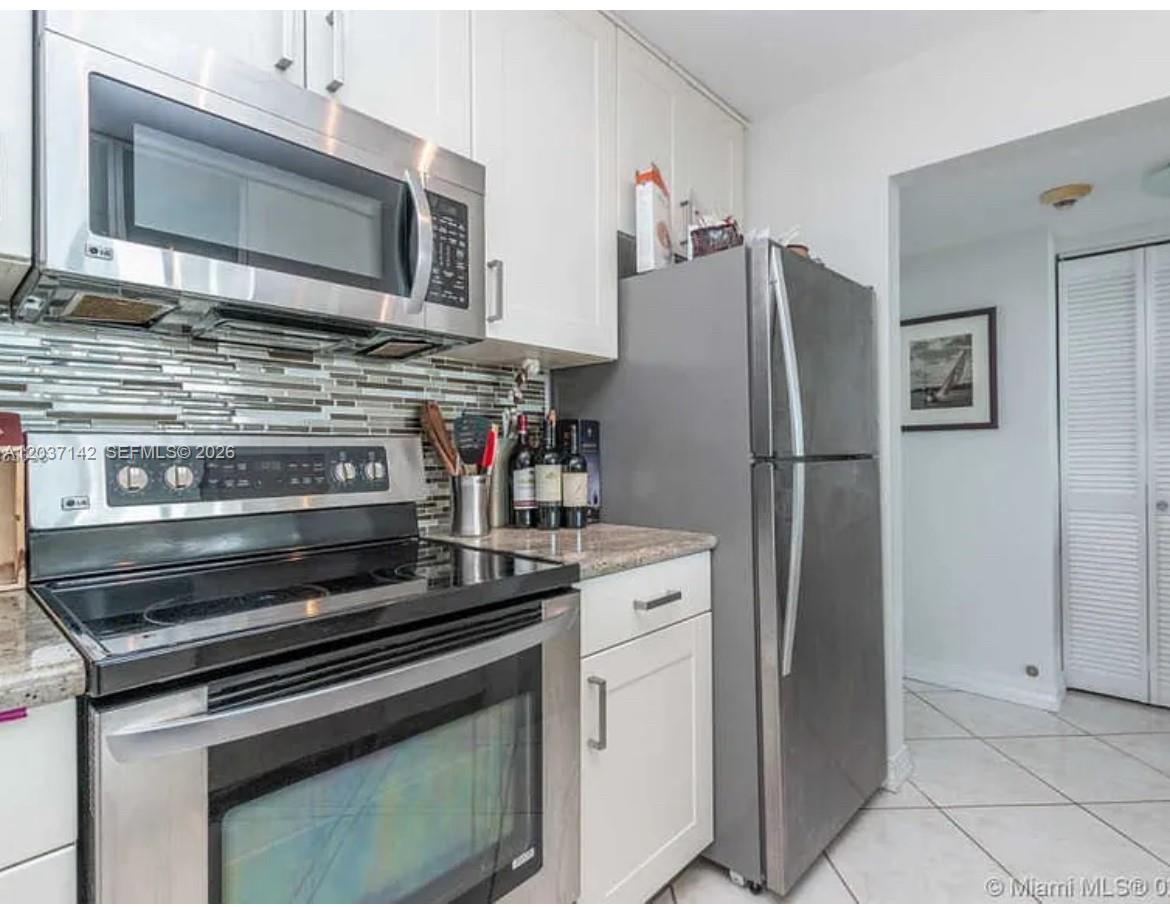 A kitchen features stainless steel appliances, white cabinets, and a tiled backsplash — 600 NE 36th St # 1006, Miami FL 33137, MIAMI, FL