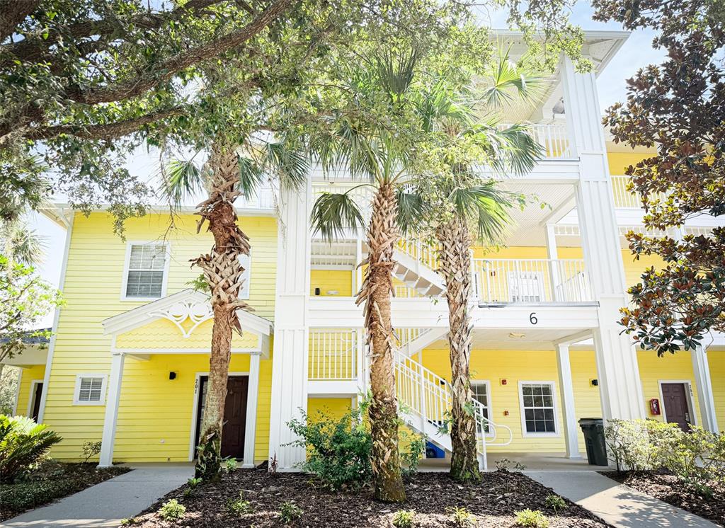 A yellow multi-story apartment building features white trim, palm trees, and an exterior staircase — 205 LUCAYA LOOP UNIT 205, DAVENPORT, FL