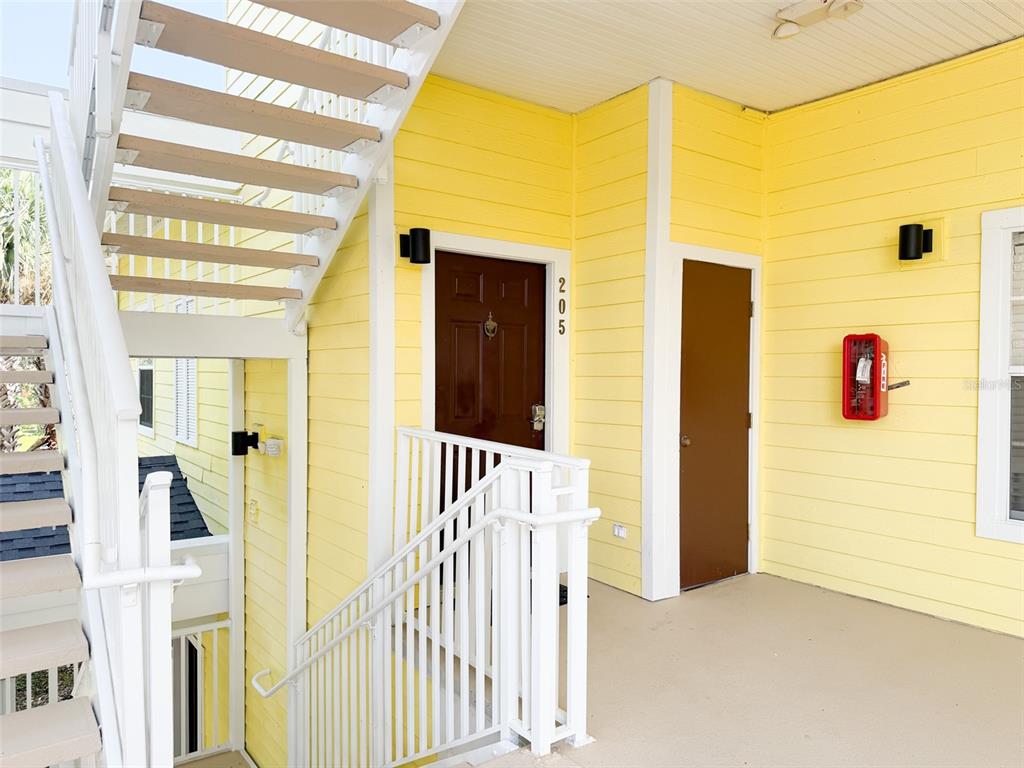 An exterior view of a yellow building entrance with a staircase and unit number 205 — 205 LUCAYA LOOP UNIT 205, DAVENPORT, FL