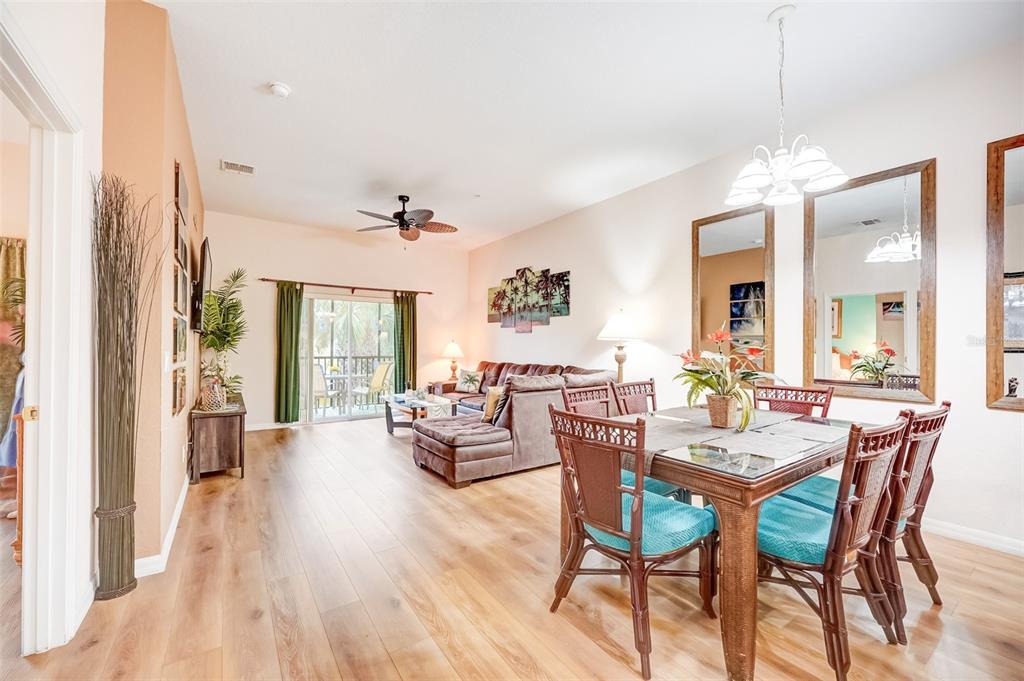 An open-concept living and dining area features wood-look flooring, a brown sectional, and rattan chairs — 205 LUCAYA LOOP UNIT 205, DAVENPORT, FL
