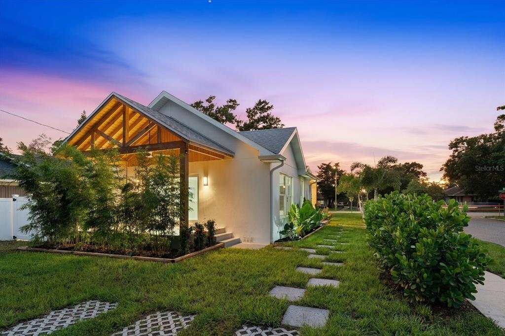 A modern white house features a wooden-beamed covered porch and a stone paver walkway — 4847 DR MARTIN LUTHER KING JR STREET N, ST PETERSBURG, FL