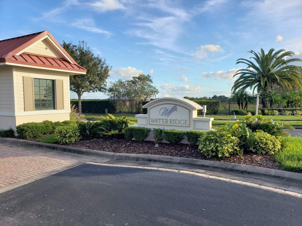 The entrance sign for Water Ridge stands in front of a guardhouse and palm trees — 295 SPINNAKER COURT, AUBURNDALE, FL