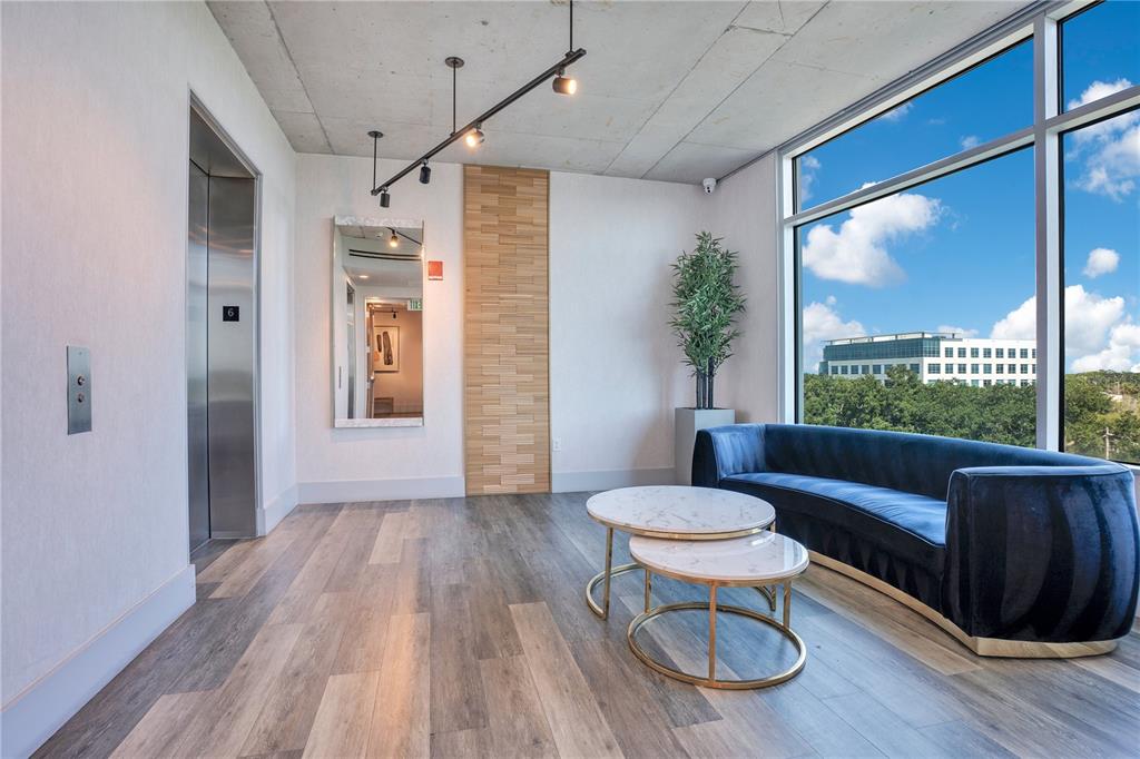 A modern waiting area features a blue velvet sofa, marble coffee tables, and floor-to-ceiling windows — 525 E JACKSON STREET UNIT 604, ORLANDO, FL