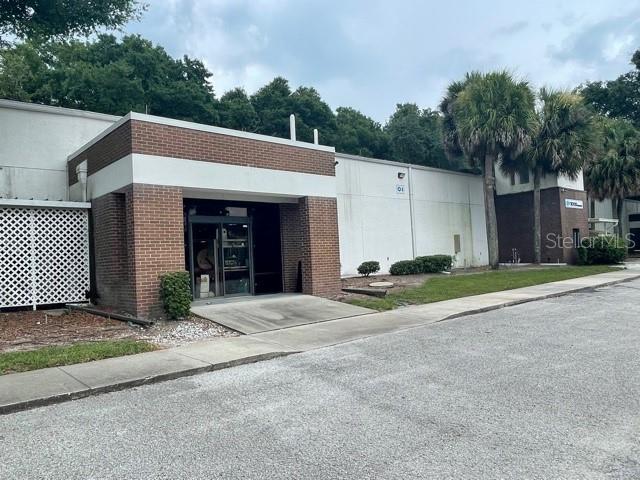 A brick and white exterior of a commercial building with a glass entrance door — 7725 N ORANGE BLOSSOM TRAIL, ORLANDO, FL