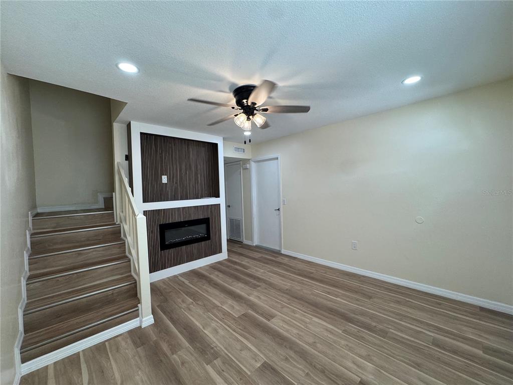 A living room features wood-look flooring, a fireplace with wood-slat paneling, and a staircase — 665 W JUNIATA STREET, CLERMONT, FL