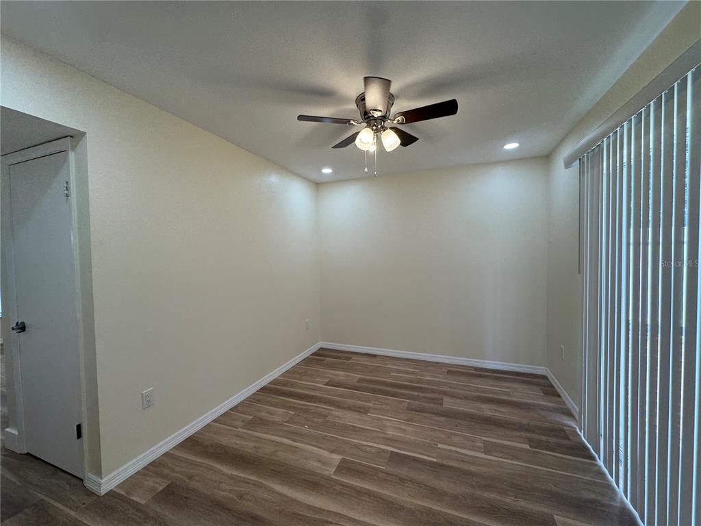 An empty room features light-colored walls, wood-look flooring, a ceiling fan, and vertical blinds — 665 W JUNIATA STREET, CLERMONT, FL