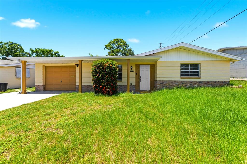 A single-story house with yellow siding, a brick base, and an attached carport — 3849 LUMA DRIVE, HOLIDAY, FL