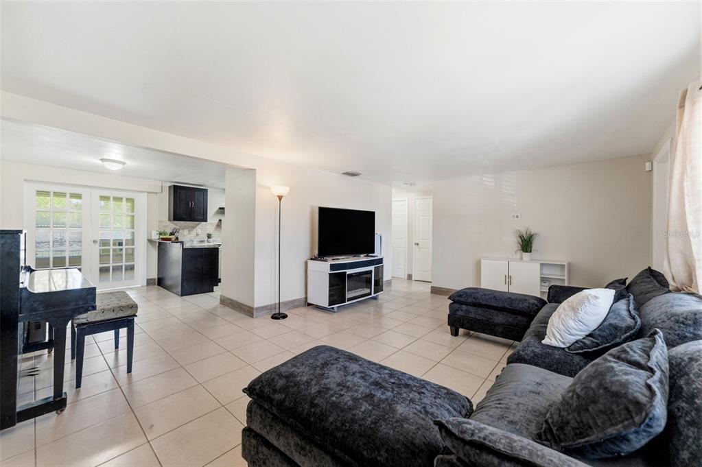 A living room with tile floors, a dark sectional sofa, a television, and a piano — 3849 LUMA DRIVE, HOLIDAY, FL