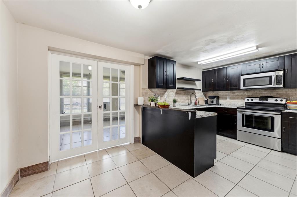 A kitchen with dark cabinets, stainless steel appliances, a breakfast bar, and glass French doors — 3849 LUMA DRIVE, HOLIDAY, FL