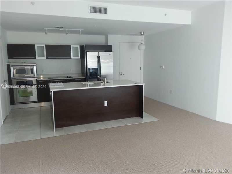 A modern kitchen features dark wood cabinetry, stainless steel appliances, and a central island — 1900 N Bayshore Dr # 3517, Miami FL 33132, MIAMI, FL