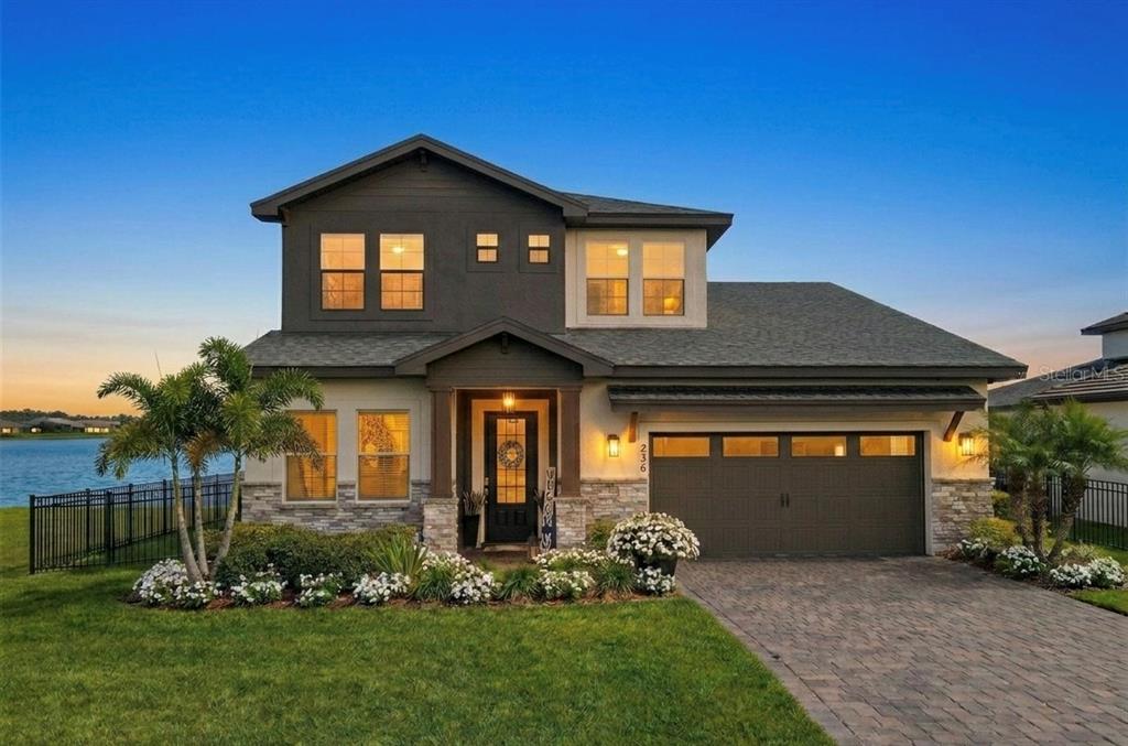 A two-story house with a dark brown garage, stone accents, and a waterfront backyard — 236 CALADIUM AVENUE, LAKE ALFRED, FL
