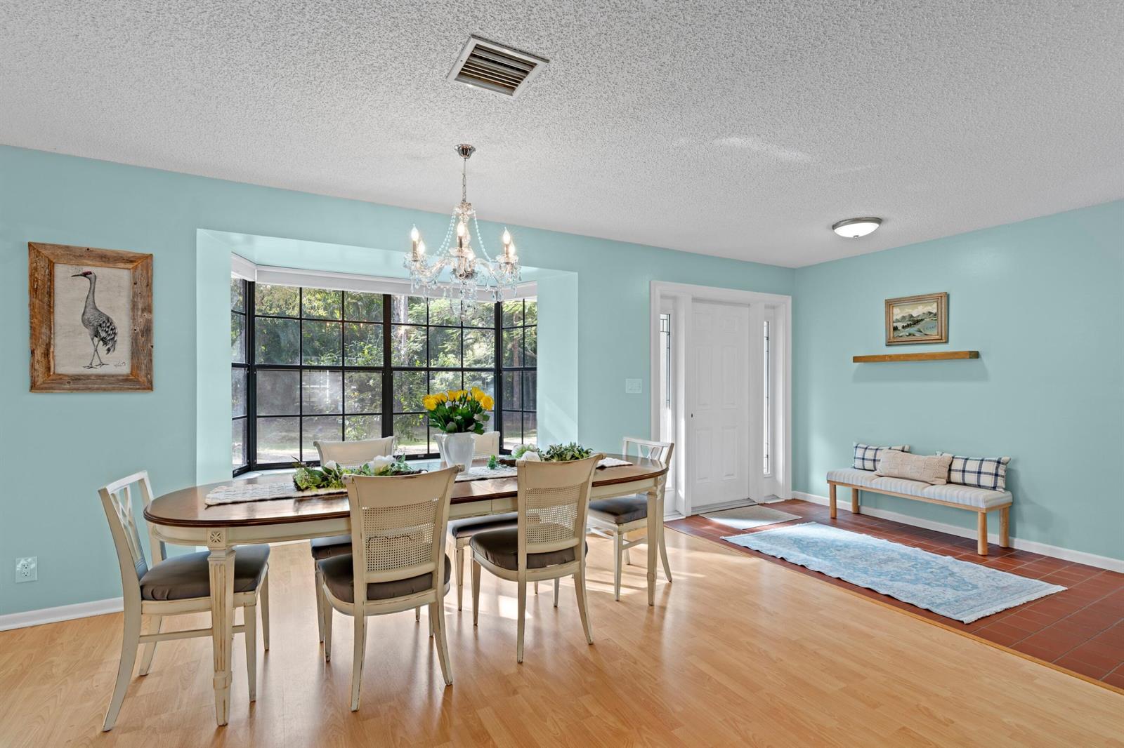 A dining room with light blue walls, a wooden table, and a bay window — 14817 Snail Trail, FL 33470, FL
