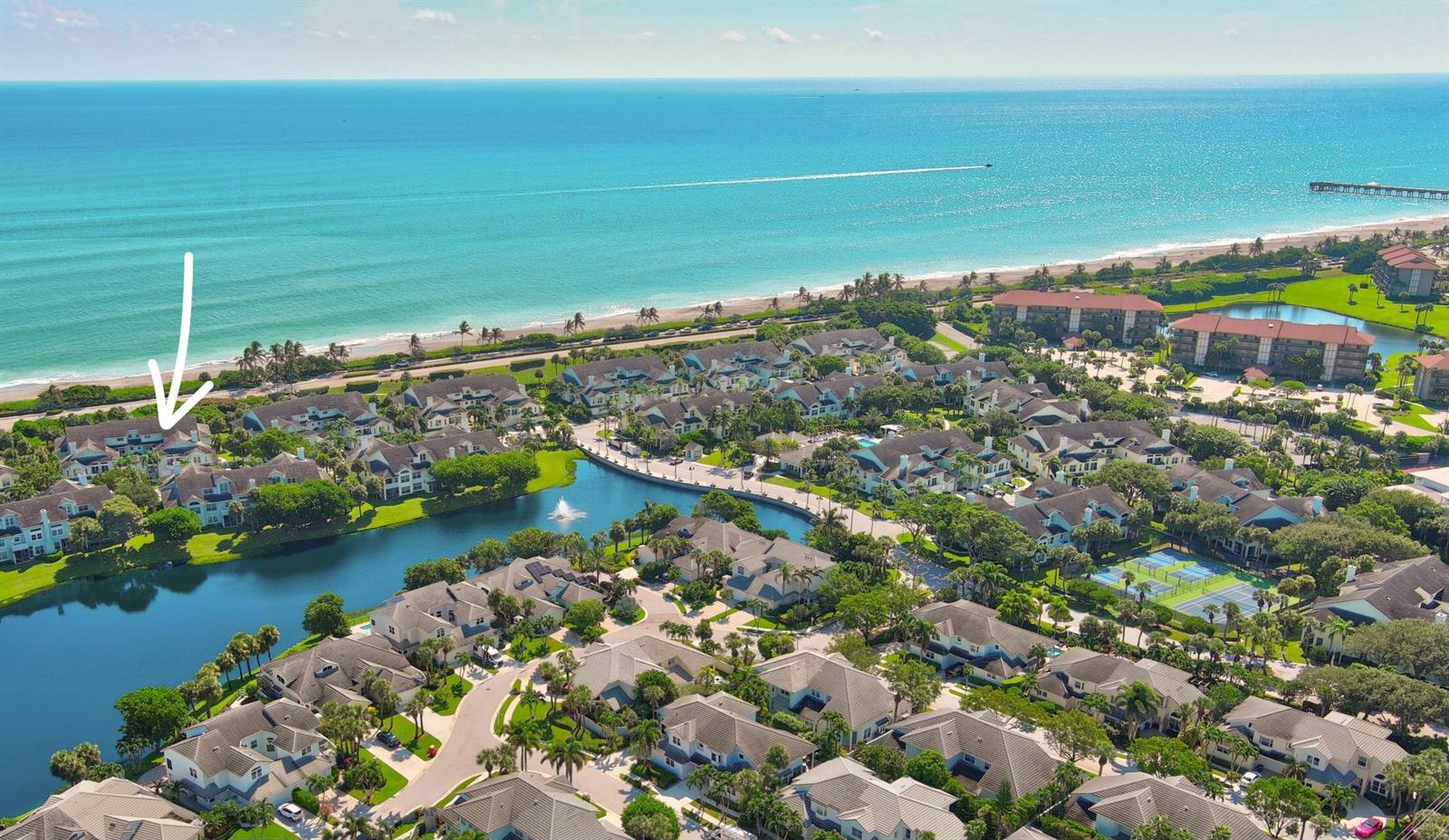 An aerial view shows a coastal residential community with a lake and nearby beach — 606 Mainsail Circle, Jupiter FL 33477, JUPITER, FL