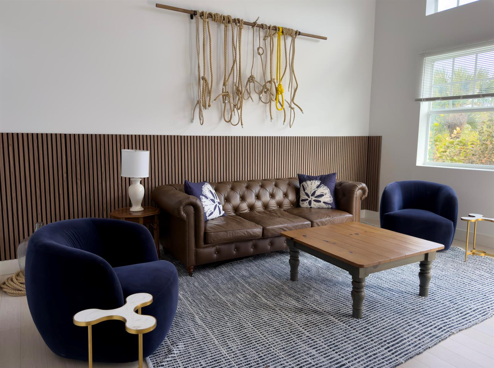 A living room features a brown leather sofa, two navy chairs, and wood slat wall paneling — 606 Mainsail Circle, Jupiter FL 33477, JUPITER, FL