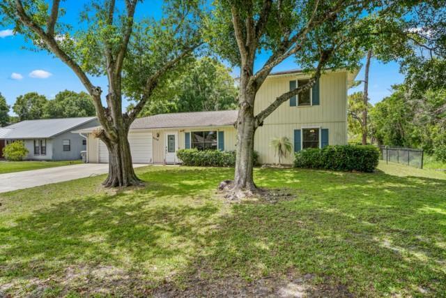 A two-story house with light-colored siding and a front lawn featuring two large trees — VERO BEACH, FL