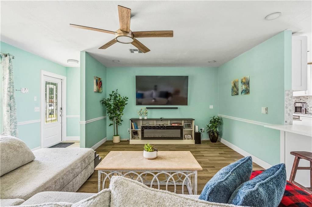 A living room features light green walls, a ceiling fan, and a television above a console — VERO BEACH, FL