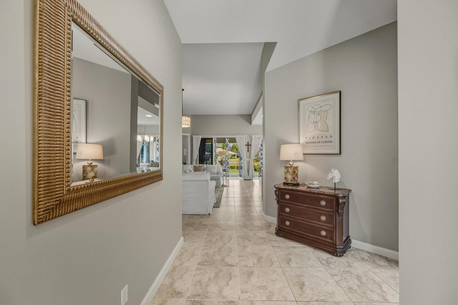 A tiled entryway features a mirror, a wooden chest, and a view into the living room — 8049 Nevis Place, Wellington FL 33414, WELLINGTON, FL