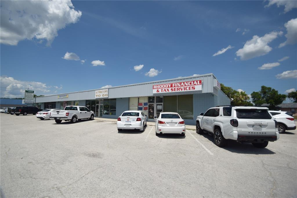 A single-story commercial building with multiple storefronts and a parking lot under a blue sky — 835/837 N LAKE PARKER AVENUE UNIT 835/837, LAKELAND, FL
