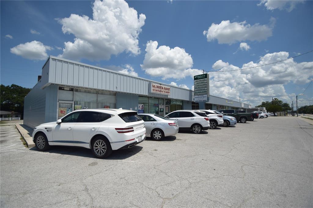 A row of commercial storefronts with a parking lot under a blue sky — 835/837 N LAKE PARKER AVENUE UNIT 835/837, LAKELAND, FL