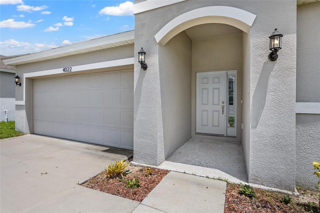 The exterior of a house features a garage, a covered entryway, and a white door — 4022 ALISSA LANE, HAINES CITY, FL
