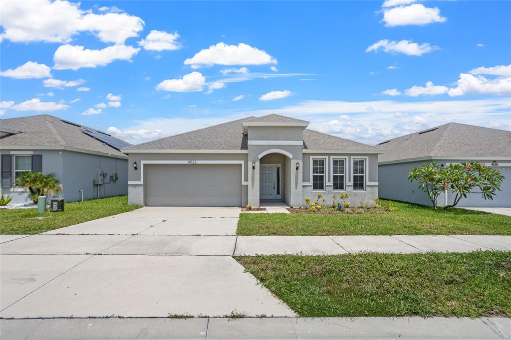 A single-story suburban house features a two-car garage, a covered entryway, and a grassy lawn — 4022 ALISSA LANE, HAINES CITY, FL