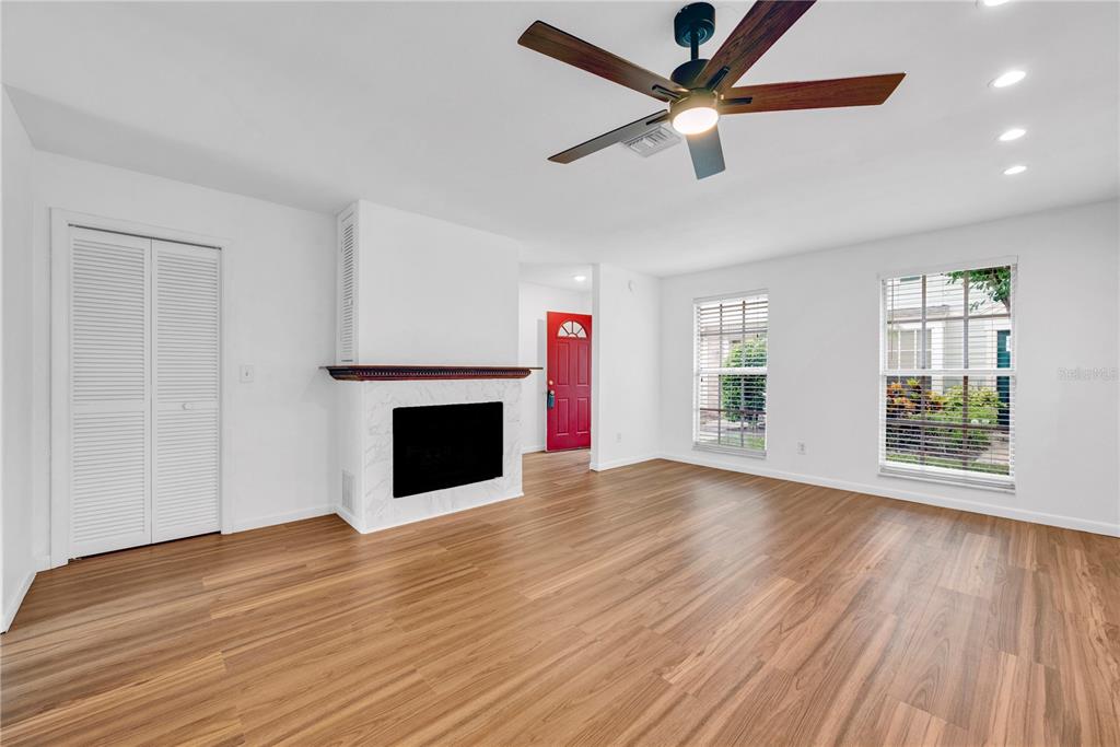 A living room features wood-look flooring, a white fireplace, and a red front door — 13915 FLETCHERS MILL DRIVE, TAMPA, FL