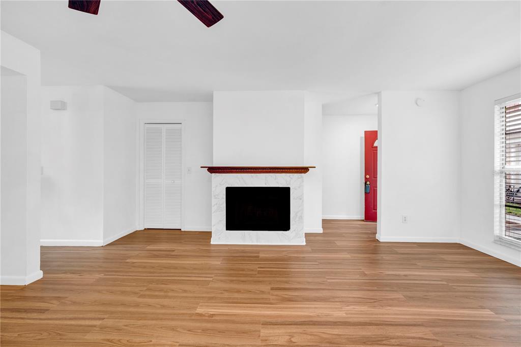 A living room with wood-look flooring, a white fireplace with a mantel, and a red door — 13915 FLETCHERS MILL DRIVE, TAMPA, FL