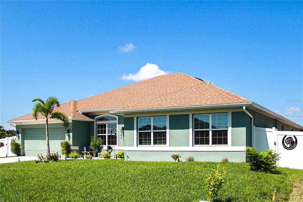 A single-story house with a light green exterior, a tan shingled roof, and a palm tree — 10125 AUDREY STREET, PORT CHARLOTTE, FL