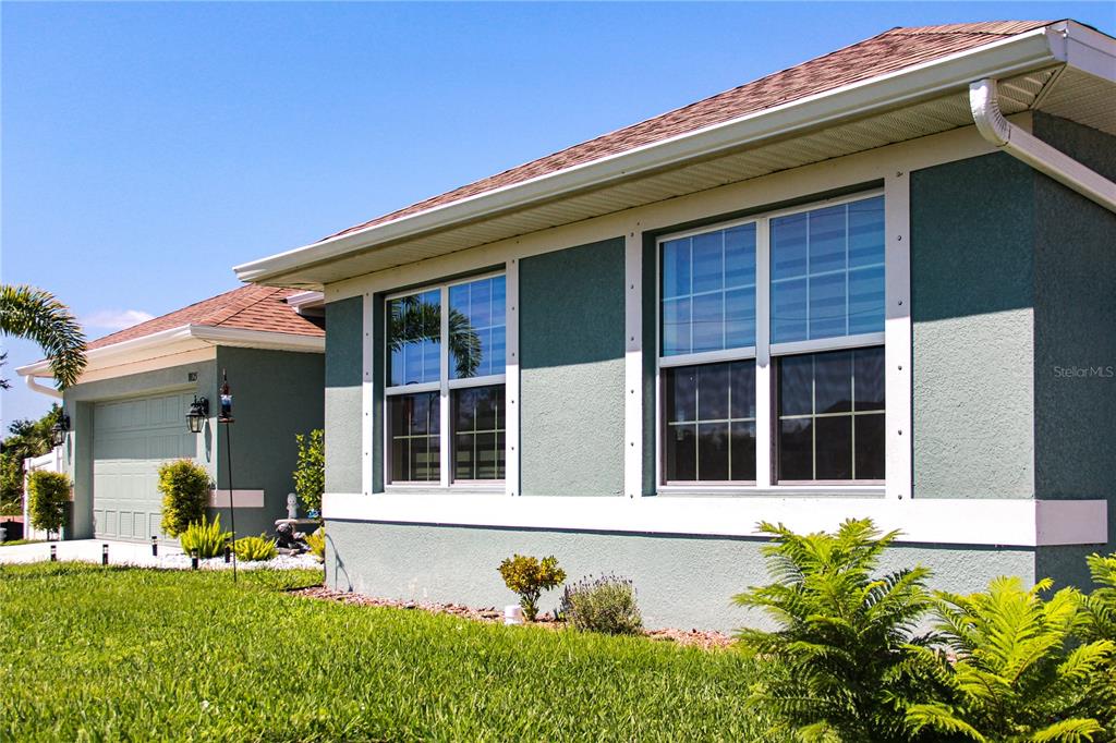 The exterior of a teal-colored house features white trim, two windows, and a garage — 10125 AUDREY STREET, PORT CHARLOTTE, FL