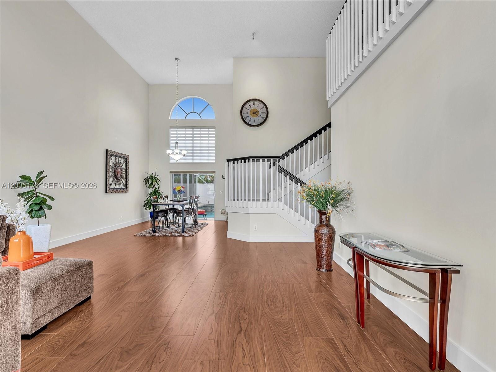 A spacious living and dining area features wood-look flooring, high ceilings, and a staircase — 2654 SW 181st Ter, Miramar FL 33029, MIRAMAR, FL