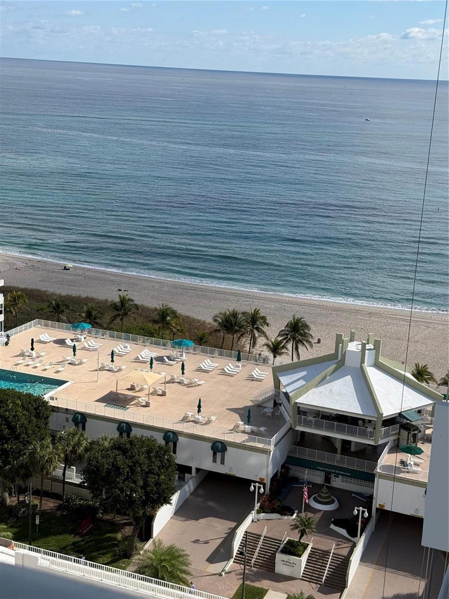 An elevated view shows a beach resort with a pool deck, palm trees, and ocean — 111 Briny Avenue # 1909, Pompano Beach FL 33062, POMPANO BEACH, FL