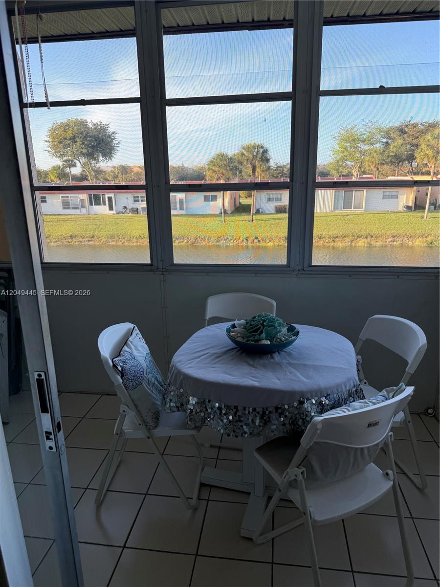 A screened-in patio features a round table with four chairs overlooking a canal and houses — WEST PALM BEACH, FL
