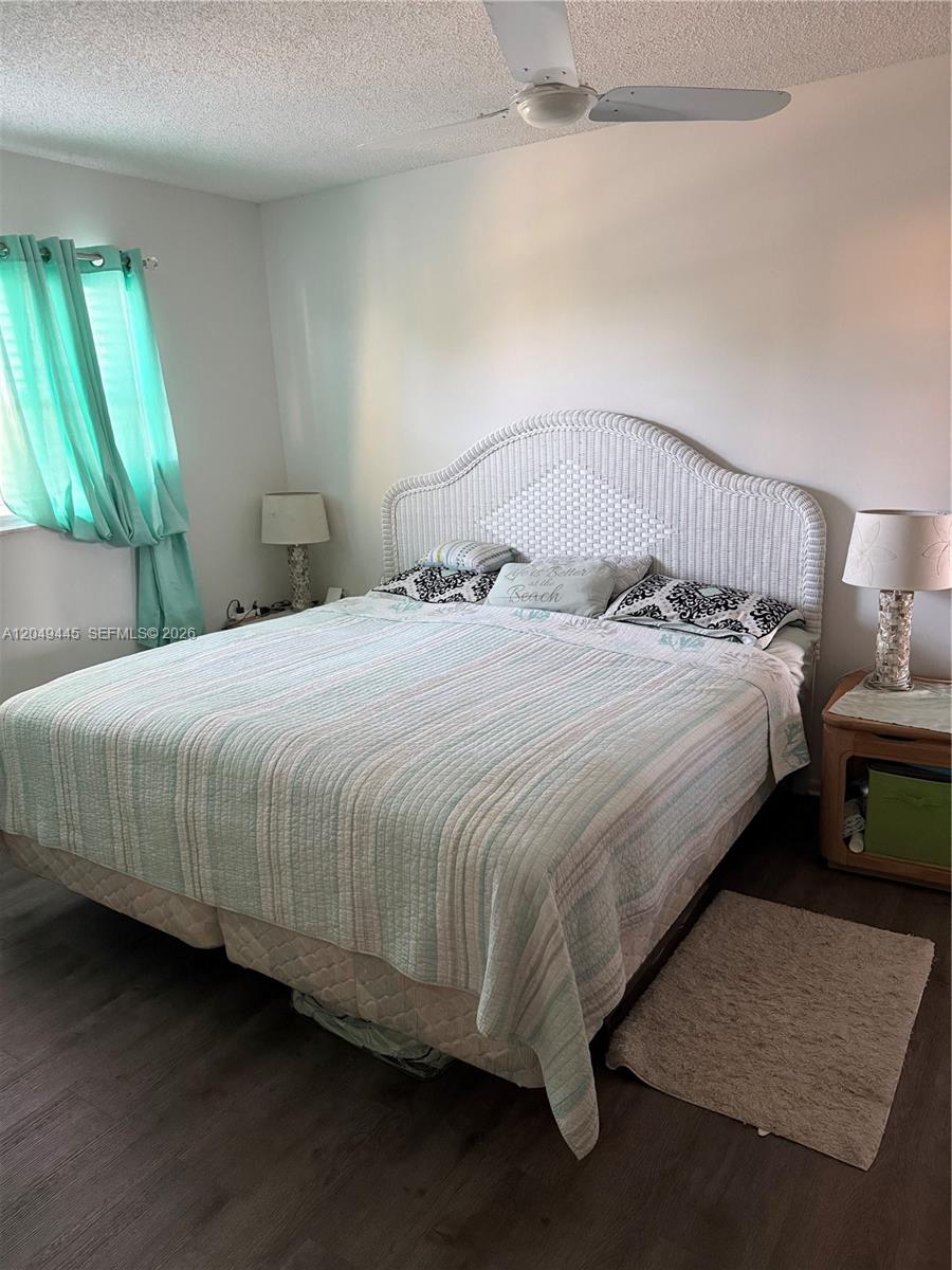 A bedroom features a white wicker headboard, a patterned quilt, and teal curtains — WEST PALM BEACH, FL