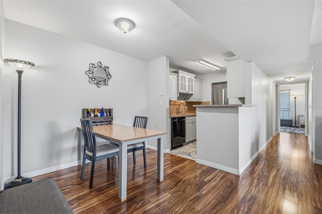 A dining area with a wooden table and chairs sits adjacent to a small kitchen — 455 ALT 19 S UNIT 163, PALM HARBOR, FL
