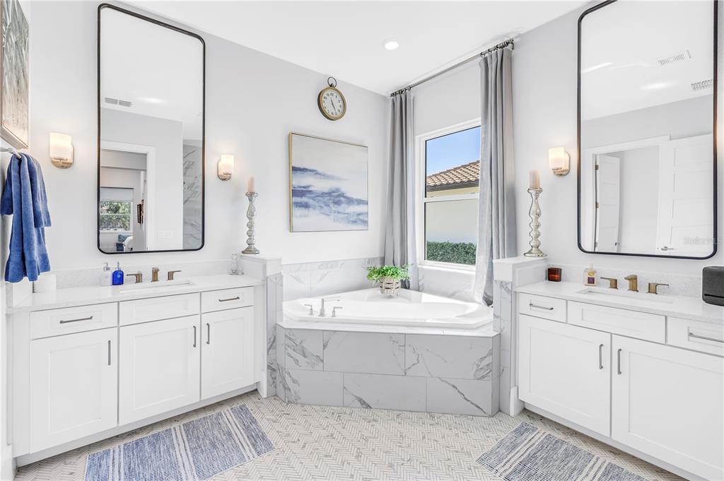 A primary bathroom features dual white vanities, a corner soaking tub, and marble-style tile flooring — 513 17TH AVENUE E, PALMETTO, FL