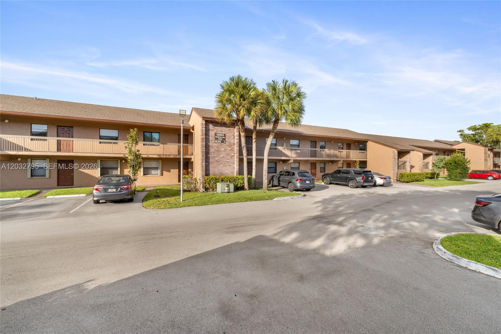 A two-story apartment building with a brick facade, palm trees, and a parking lot — 10003 Winding Lake Rd # 203, Sunrise FL 33351, SUNRISE, FL