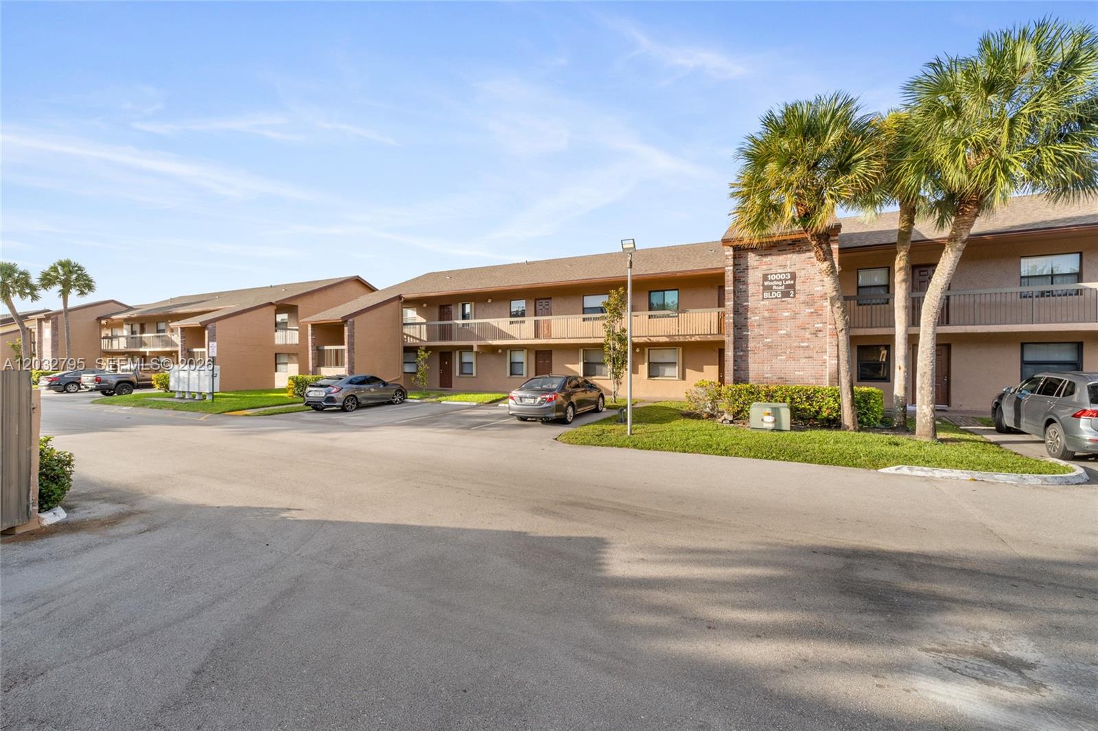A two-story apartment building with a brick facade, palm trees, and a parking lot — 10003 Winding Lake Rd # 203, Sunrise FL 33351, SUNRISE, FL