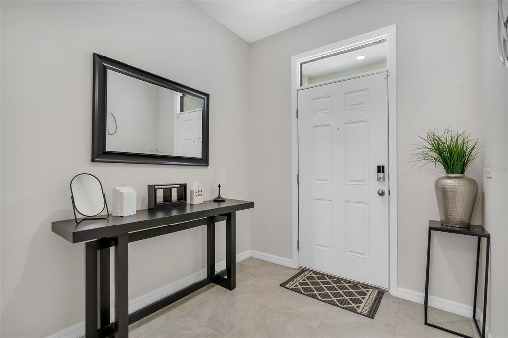 A bright entryway features a white front door, a black console table, and a wall mirror — 11175 CRESCENT DEER DRIVE, LAND O LAKES, FL