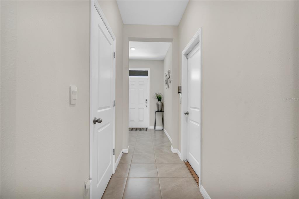 A hallway with light-colored tile flooring leads to a white front door — 11175 CRESCENT DEER DRIVE, LAND O LAKES, FL
