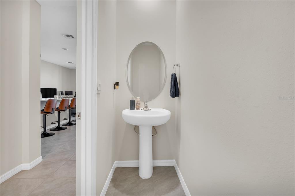 A small powder room features a white pedestal sink, an oval mirror, and neutral walls — 11175 CRESCENT DEER DRIVE, LAND O LAKES, FL