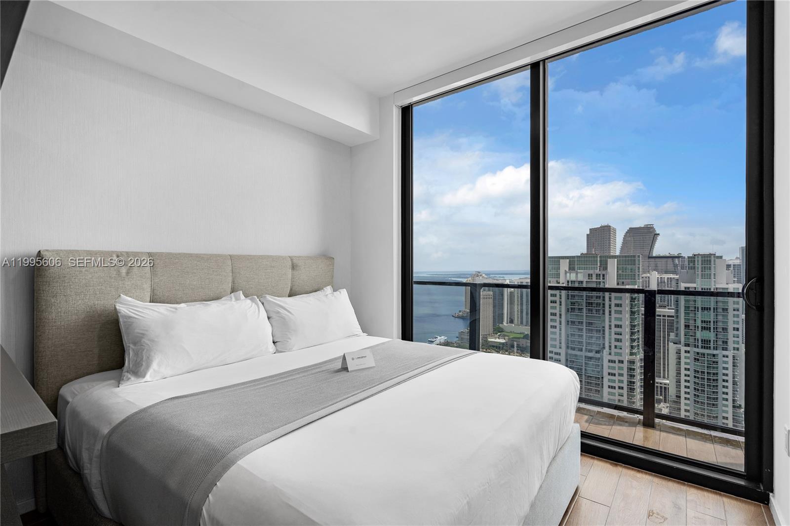 A bedroom with a queen bed and floor-to-ceiling windows overlooking a city and bay — 398 NE 5th St # 4716, Miami FL 33132, MIAMI, FL
