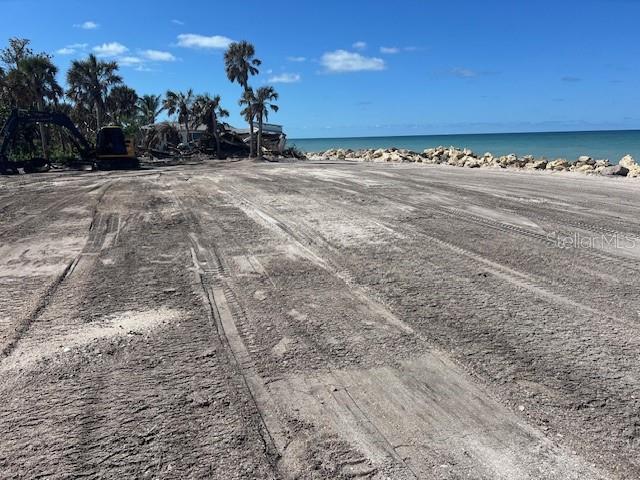 A cleared, sandy waterfront lot features heavy machinery and palm trees near the ocean — 7050 MANASOTA KEY ROAD, ENGLEWOOD, FL