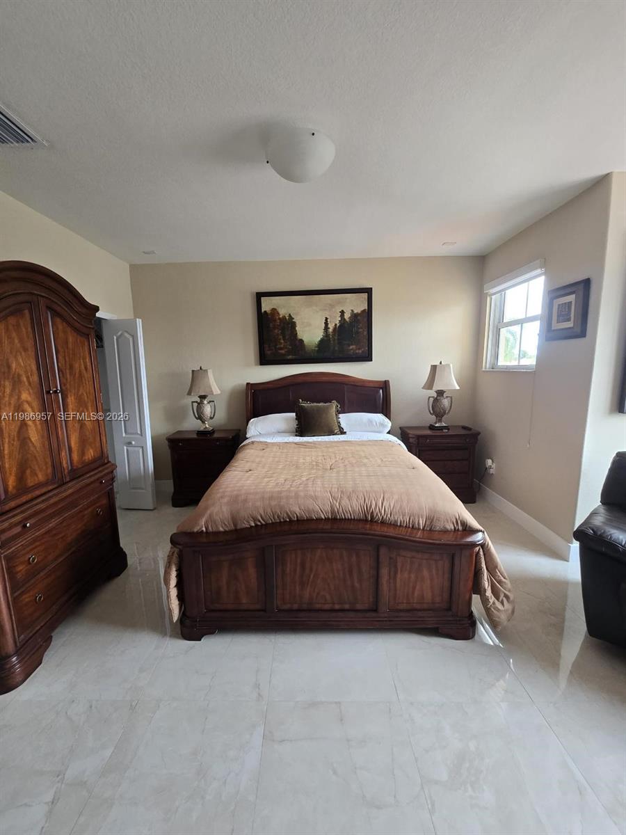 A bedroom features a wooden bed frame, matching nightstands, a large wardrobe, and tile flooring — 14978 SW 12th Ln # 0, Miami FL 33194, MIAMI, FL