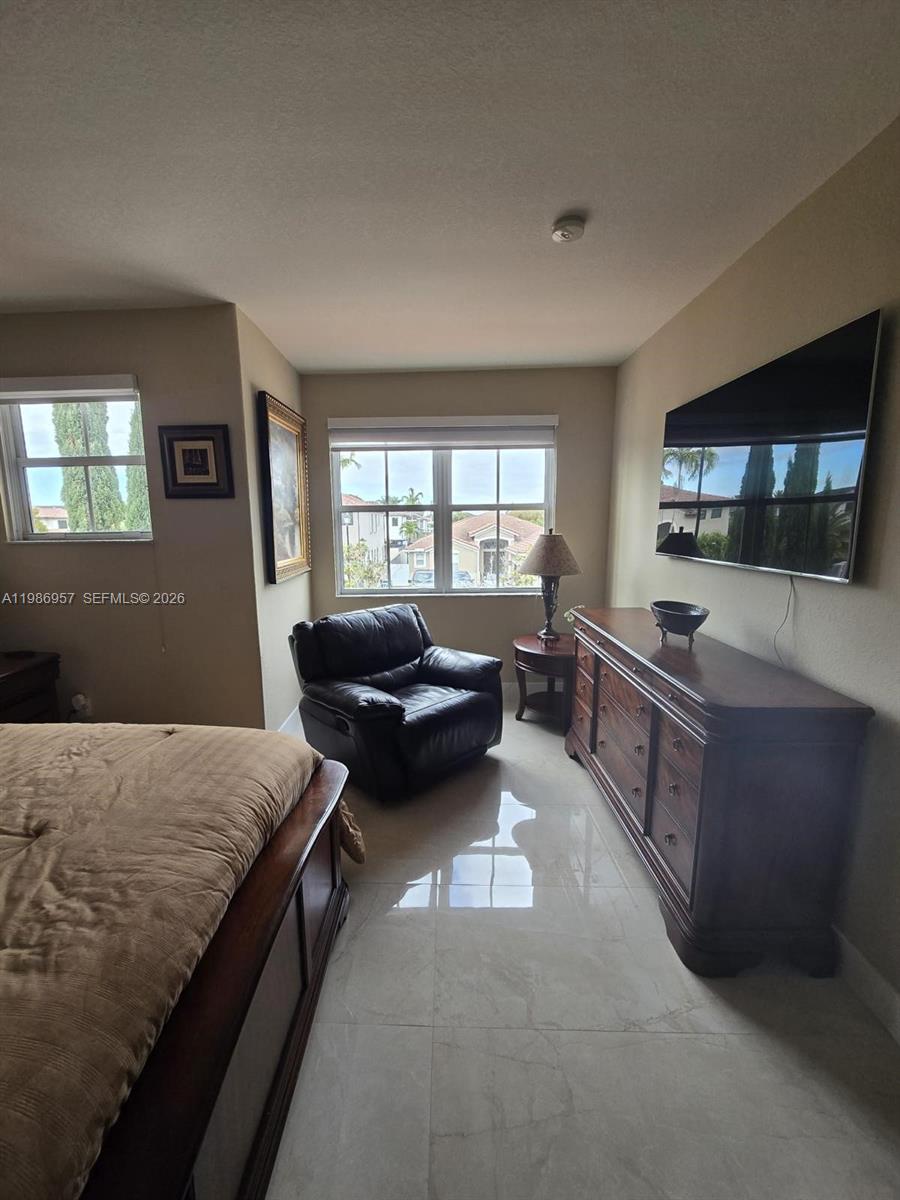 A bedroom features a leather armchair, a wooden dresser with a television, and tile flooring — 14978 SW 12th Ln # 0, Miami FL 33194, MIAMI, FL