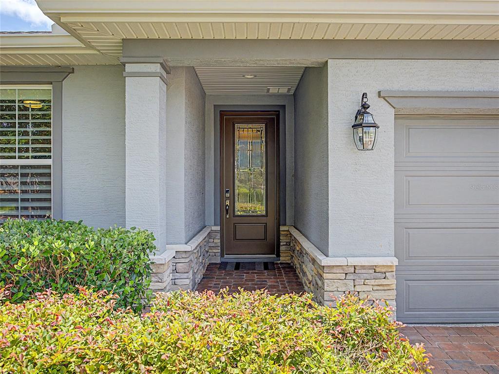 The exterior of a house features a brown front door, stone accents, and a garage — 4235 NW 55TH COURT, OCALA, FL