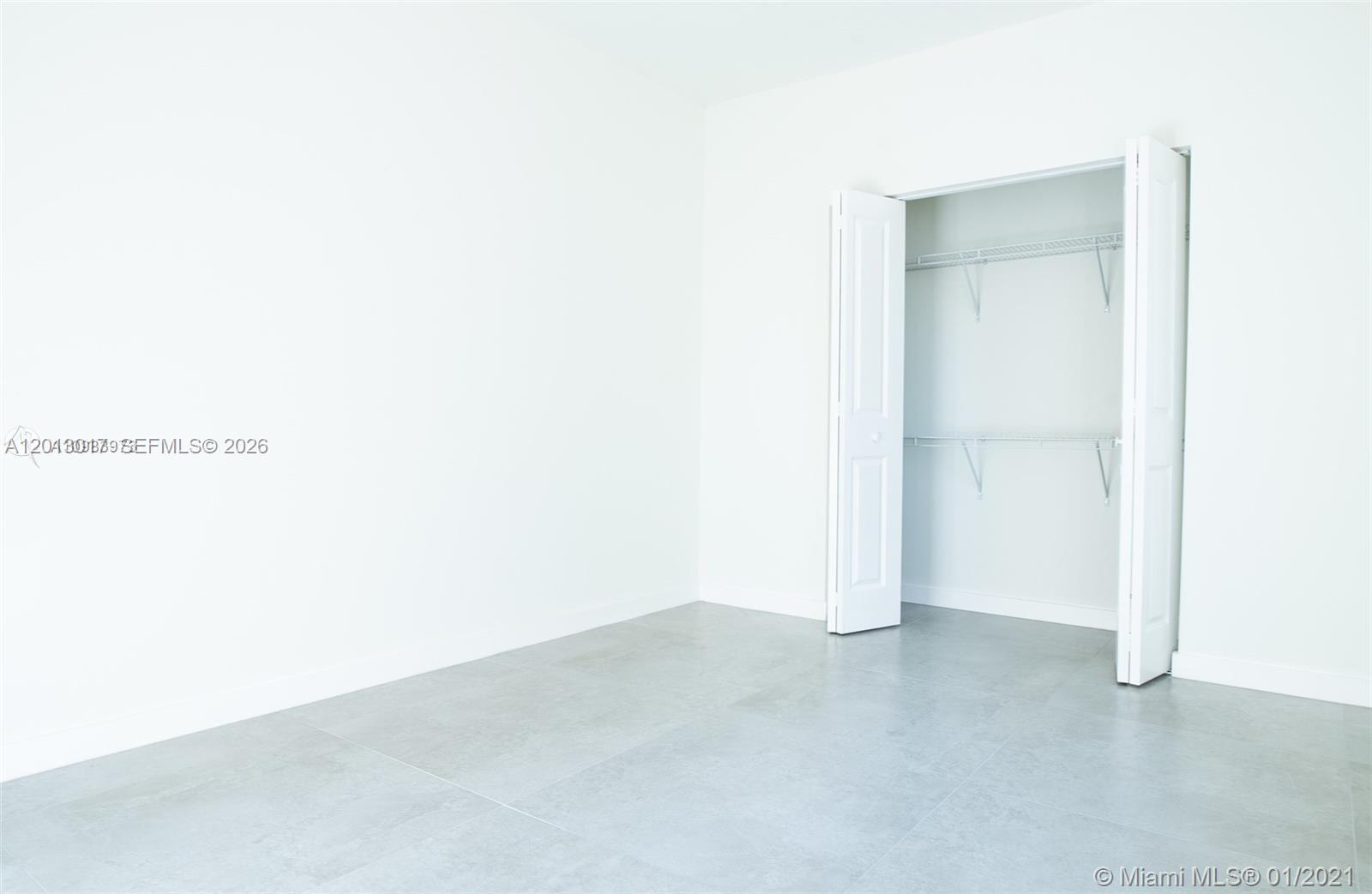 An empty room features white walls, light gray tile flooring, and an open closet — 120 NE 71st St # 3, Miami FL 33138, MIAMI, FL