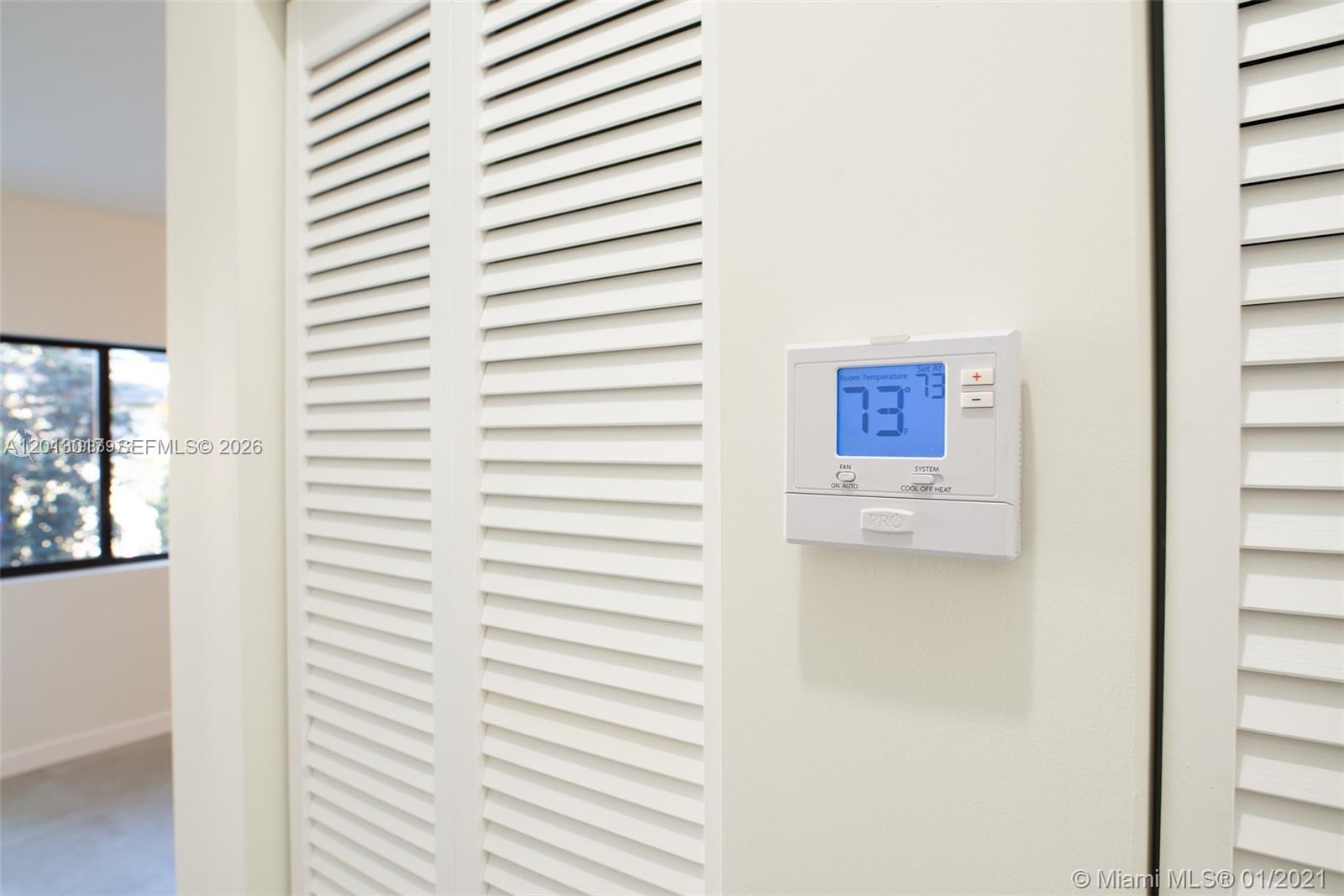 A digital thermostat is mounted on a wall next to white louvered closet doors — 120 NE 71st St # 3, Miami FL 33138, MIAMI, FL
