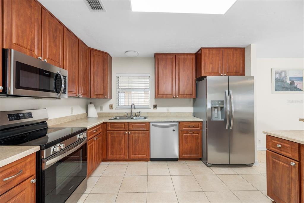 A kitchen with wood cabinets, stainless steel appliances, and tile flooring — 8593 NW 41ST TERRACE, GAINESVILLE, FL