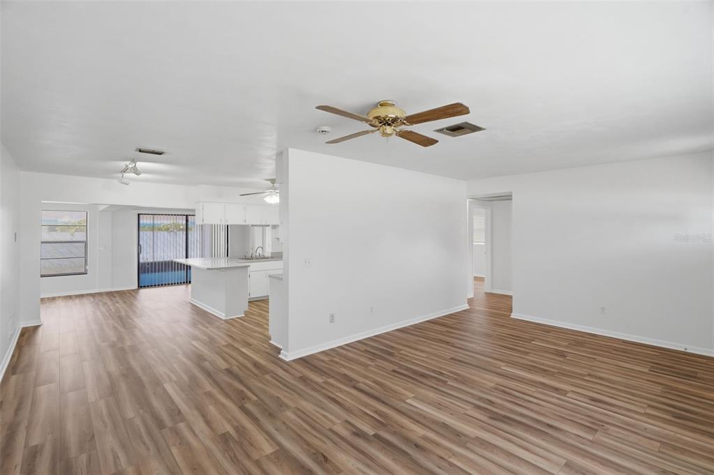 An open-concept living area features wood-look flooring, white walls, and a kitchen with a peninsula — 1981 TEMPLE TERRACE, CLEARWATER, FL