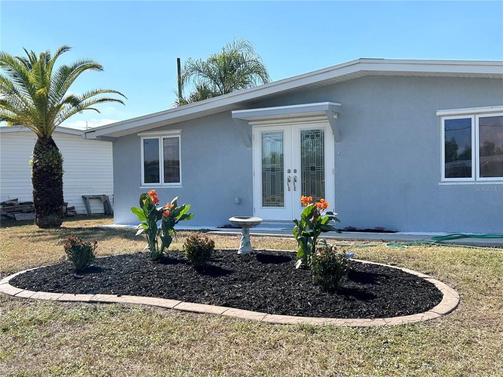 A single-story house with a gray exterior, double glass doors, and a landscaped front garden — 4127 GARDNER DRIVE, PORT CHARLOTTE, FL